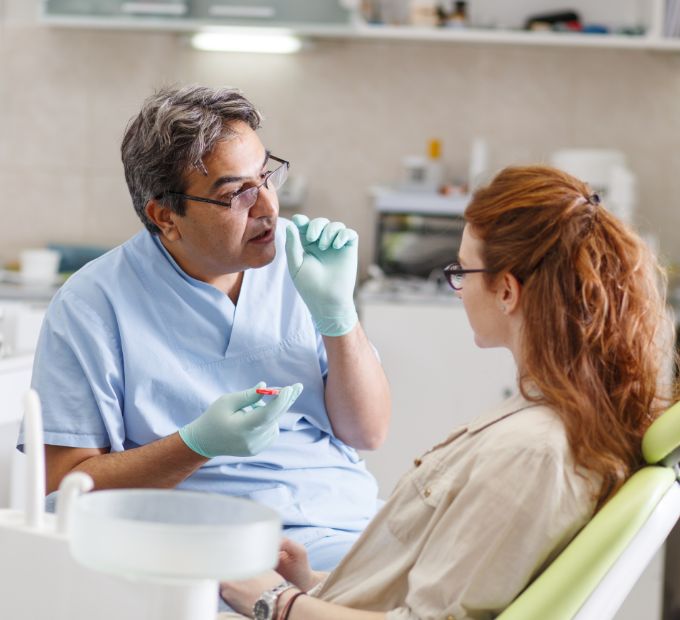 Dentist talking to a woman in the treatment chair
